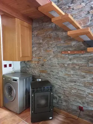 a kitchen with a washing machine and a stone wall at El Pajar de Triana in Brañuelas