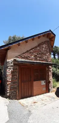 a stone building with a large wooden garage at El Pajar de Triana in Brañuelas