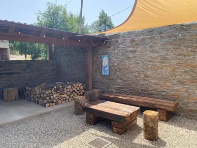 a wooden bench sitting next to a stone wall at El Pajar de Triana in Brañuelas