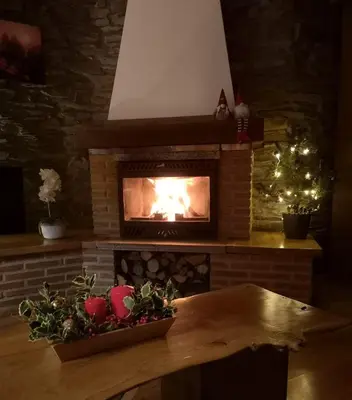 a living room with a fireplace with a christmas tree at El Pajar de Triana in Brañuelas