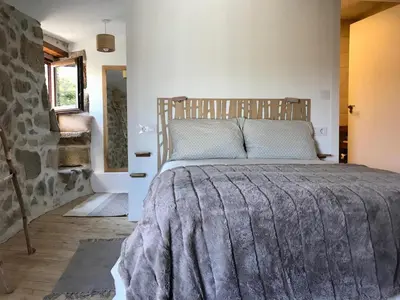 a bedroom with a large bed with a stone wall at Casa Media Lúa in Allariz