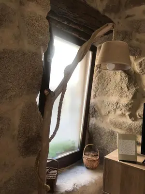 a window in a stone wall with a lamp at Casa Media Lúa in Allariz