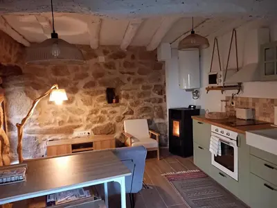 a kitchen with a table and a stone wall at Casa Media Lúa in Allariz