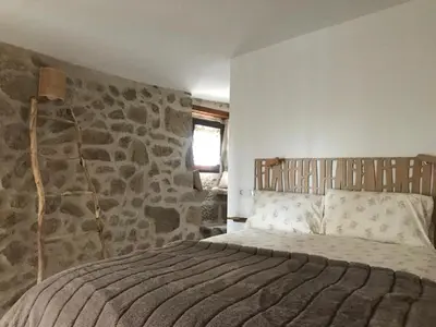 a bedroom with a bed with a stone wall at Casa Media Lúa in Allariz