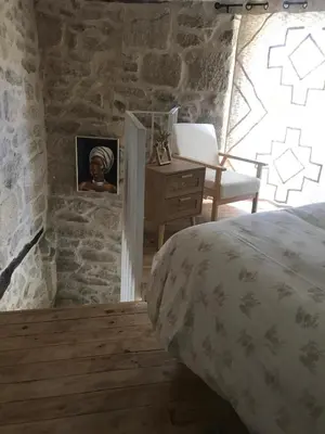 a bedroom with a bed and a desk in a stone wall at Casa Media Lúa in Allariz
