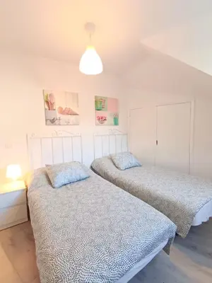 two beds in a white room with a lamp at Apartamento Maruja Mallo in Viveiro