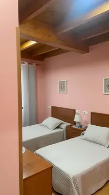 two beds in a room with pink walls at Nido 33 in Ribadeo