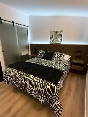 a bedroom with a bed with black and white sheets at Adiva A Zapataría in Puentedeume