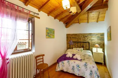 a bedroom with a bed and a chair and a window at Casa Ruperto in Doade