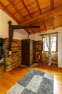 a living room with a stone wall and a wooden ceiling at Casa Ruperto in Doade