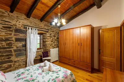 a bedroom with a bed and a stone wall at Casa Ruperto in Doade
