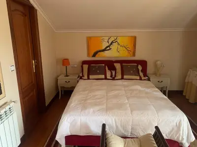 a bedroom with a large white bed with two tables at Lar do Pero - Ribeira Sacra