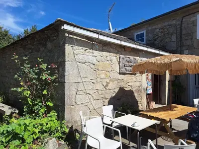 a patio with a table and chairs and an umbrella at Albergue Casa Cruceiro de Ferreiros in Ferreiros