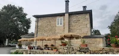 a stone building with umbrellas in front of it at Albergue Casa Cruceiro de Ferreiros in Ferreiros