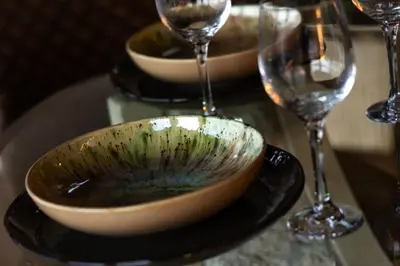 a bowl on a plate next to two wine glasses at Vencello Estelar Compostela in Santiago de Compostela