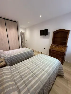 a bedroom with two beds and a tv on the wall at La Venta del Clavo in Astorga