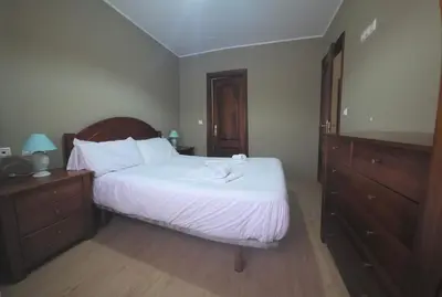 a bedroom with a bed with white sheets and a dresser at Apartamentos Camino Inglés 3 in O Mesón Do Vento