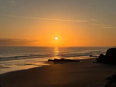 a sunset on the beach with the sun setting at Casa de Mia Beachfront Home Playa de las Catedrales Ribadeo in Pena
