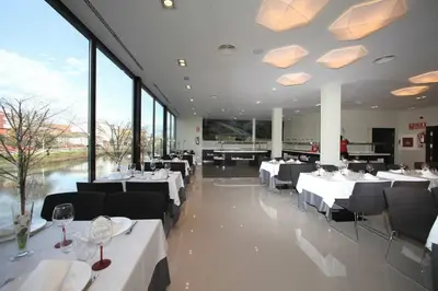 a restaurant with white tables and chairs and large windows at Hotel Cardenal in Monforte de Lemos