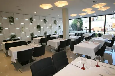 a dining room with white tables and black chairs at Hotel Cardenal in Monforte de Lemos