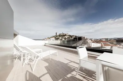 a balcony with white chairs and a view of a city at Hotel Cardenal in Monforte de Lemos