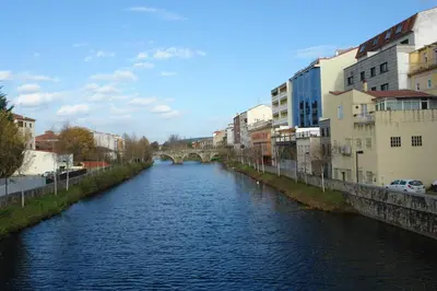 a river in a city with a bridge and buildings at Hotel Cardenal in Monforte de Lemos