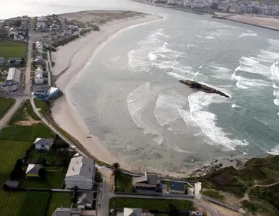 an aerial view of a beach with a rock in the water at El rincón de la Mariña in San Cosme de Barreiros