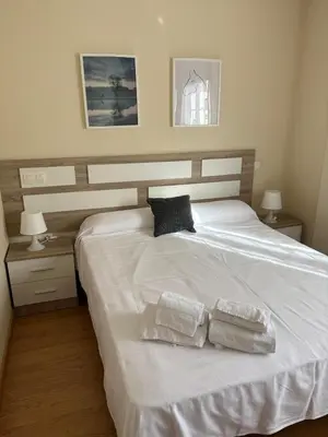 a bedroom with a white bed with two towels on it at El rincón de la Mariña in San Cosme de Barreiros
