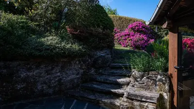 a stone path with flowers next to a building at Casa Dulcinea - casa rural en Ribeira Sacra in Serode