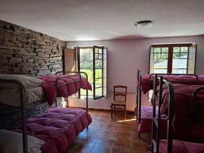 a room with a stone wall and a desk in a room at Albergue Val de Samos in Samos