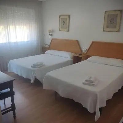 two beds in a hotel room with white sheets at Hostal los Rosales in Almázcara