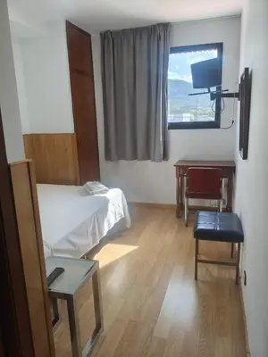 a room with two beds and a desk and a window at Hostal los Rosales in Almázcara
