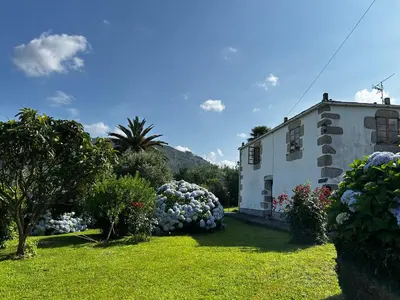 a house with a yard with bushes and flowers at Casa Conchas in O Valadouro