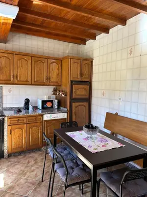 a kitchen with wooden cabinets and a table and chairs at Casa Conchas in O Valadouro