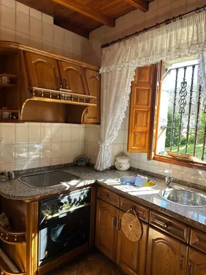 a kitchen with wooden cabinets and a sink and a window at Casa Conchas in O Valadouro