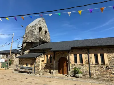 an old stone church with flags hanging above it at Casa Rural Ucedo in Ucedo