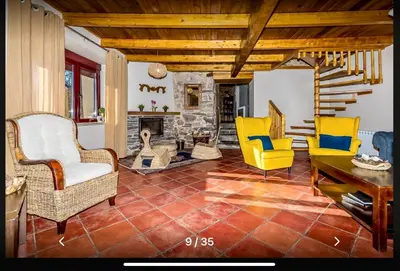 a living room with yellow chairs and a stone fireplace at Casa Rural Ucedo in Ucedo