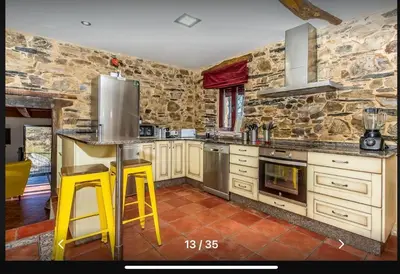 a kitchen with yellow stools in a stone kitchen at Casa Rural Ucedo in Ucedo