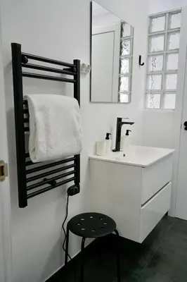 a white bathroom with a sink and a stool at Apartamentos Campus Arzúa in Arzúa
