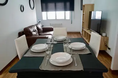a dining room table with plates and wine glasses on it at Apartamentos Campus Arzúa in Arzúa