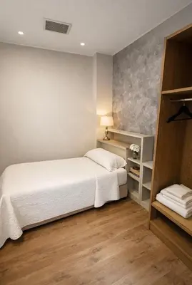 a bedroom with a white bed and wooden floors at hostal Saint James Way in Cacabelos