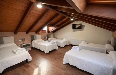 a attic room with four beds and wooden ceilings at hostal Saint James Way in Cacabelos