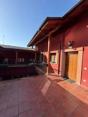 an outside view of a red building with a patio at hostal Saint James Way in Cacabelos
