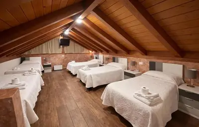 a room with four beds in a room with wooden ceilings at hostal Saint James Way in Cacabelos
