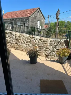 a stone wall and two potted plants in front of a building at Alojamientos as moras arans in La Cañiza