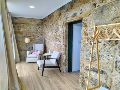 a room with a stone wall with a chair and a ladder at Alojamiento cruceiro Arans in La Cañiza