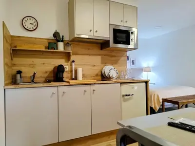 a kitchen with white cabinets and a clock on the wall at Alojamiento piñeiro arans in Oroso