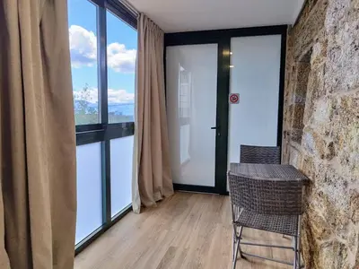 a room with glass doors and a table and chair at Alojamiento piñeiro arans in Oroso