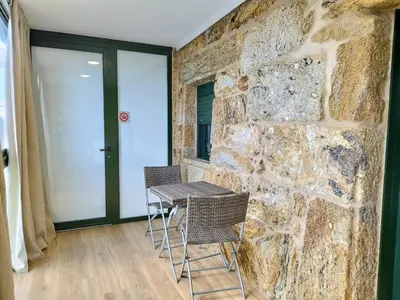 a table and chairs in a room with a stone wall at Alojamiento piñeiro arans in Oroso