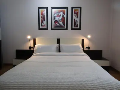 a bedroom with a large white bed with three pictures on the wall at Atico centrico Lela Lemos-3 habitaciones y 3 baños in Monforte de Lemos